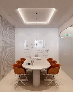 a white table surrounded by orange chairs in front of a wall with writing on it