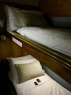 there is a small bed with white sheets and pillows on the bottom bunk, next to a pillow