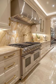 a kitchen with marble counter tops and white cabinets, along with stainless steel oven hoods