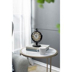 an alarm clock sitting on top of a table next to a cup and saucer