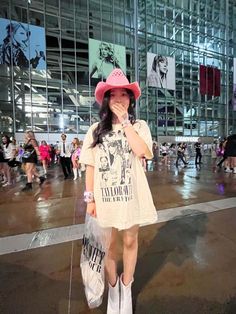 a woman wearing a pink hat and white dress is standing in front of a building