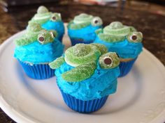 cupcakes with blue frosting and green sea turtle decorations on top are sitting on a white plate