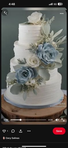 a white wedding cake with blue flowers and leaves on the top is being viewed in an instagram