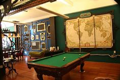 a room with a pool table, chairs and a map on the wall behind it