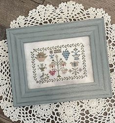 a framed picture on a doily next to a small piece of paper with an embroidered design