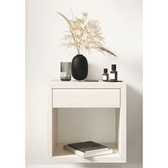 a white table topped with a vase filled with flowers next to a book and two candles