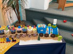 a table topped with lots of cupcakes covered in frosting next to a stair case