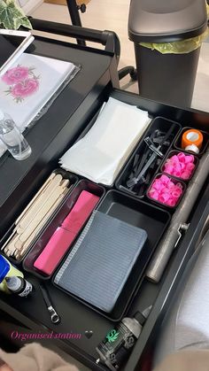 an organized drawer on a table in a living room or office space with papers, pens and other items