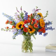 a vase filled with lots of colorful flowers next to a book on top of a table