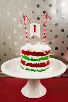 a red, green and white cake with two candles on it sitting on a table