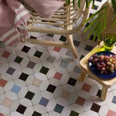 a plate of grapes sits on a small table next to a wicker chair and potted plant