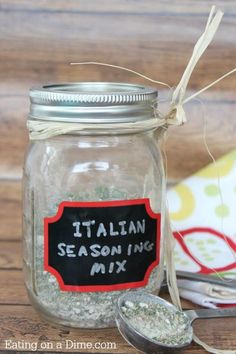 a mason jar filled with italian seasoning mix next to a spoon and napkin on a wooden table