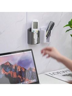 a laptop computer sitting on top of a desk next to a phone and pen holder