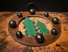 a wooden christmas tree surrounded by bells on a brown surface with black balls around it