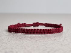 a close up of a red string bracelet on a white counter top with space for text