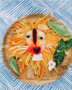 a lion made out of pasta on top of a wooden plate with leaves and flowers