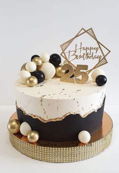 a white and black birthday cake with gold decorations