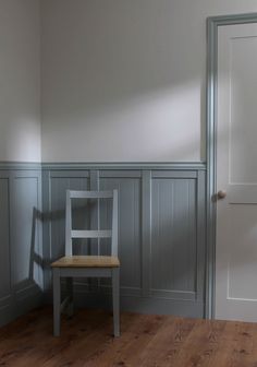 a chair sitting in the corner of a room with gray paneling on the walls