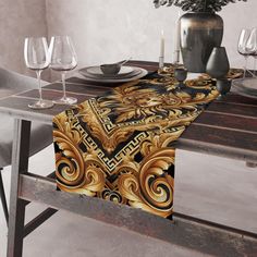 the table runner is decorated with gold and black art nouveau designs, along with wine glasses