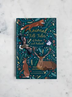 an animal folk tales book on a marble surface with birds and deer in the background