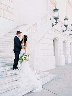 a bride and groom are standing on the stairs