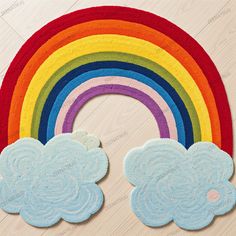 a rainbow rug with two clouds and a rainbow in the middle on a wooden floor