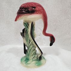 a flamingo figurine sitting on top of a white surface