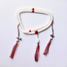 This Mala is made of Natural White Bodhi Root Beads (6x8mm, one type of bodhi seeds) with Genuine 90% Red Cinnabar Spacer Beads (8mm), Guru Bead (12mm), and Bell Vajra Copper Mala Counters, in Non-stretchy Strong Multicolor Cotton Thread. M A L A ♡ This mala is about 27 inches (6x8mm beads) in length, with another 2 inches adjustable length at the bottom of the guru knot.  ♡ The pair of mala counters can be detached from the mala.  M A L A . B A G ♡ An anti-oxidation bag is included with this ma White Beaded Mala For Festivals, White Bohemian Mala For Puja, White Beaded Mala For Puja, Traditional White Mala With Gemstone Beads, White Beaded Spiritual Mala, Cotton Thread, Spacer Beads, Copper, Beads