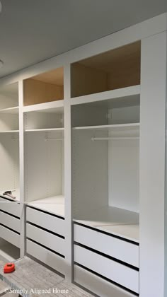 an empty walk - in closet with white drawers and shelving units on the wall