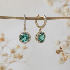 Singular seafoam green tourmaline gemstones situate in a halo of diamonds on each earring of this 2-piece set. Genuine natural light brown diamonds line both the hoops and halos in solid 14k yellow gold. Elegant Round Tourmaline Earrings, Round Tourmaline Gemstone Earrings, Round Tourmaline Jewelry With Halo Setting, Brown Diamonds, Round Light, Tourmaline Pendant, Brown Diamond, Huggie Earrings, Hook Clasp