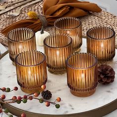 four glasses on a table with pine cones and other items around it, including a candle holder