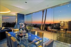 the dining room table is surrounded by chairs and glass walls that look out onto the city