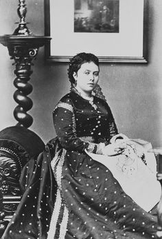 an old black and white photo of a woman sitting on a bed