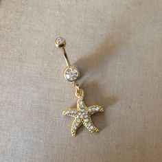 Gold Starfish Belly Button Ring - gold belly ring, crystal belly ring, beach lover gift Pretty belly ring in surgical steel colored GOLD with a double gem in clear and a rhinestone encrusted starfish with embossed detal (shown in hand in silver)   entire piece approx 1 5/8" long. /42mm 14 gauge Large barbell rhinestone approx 7mm across - star pendant Approx 7/8 (24mm) long  Comes in an organza gift bag matching necklace available To keep the rhinestones looking their best I recommend you do not Starfish Belly Button Piercing, Gold Belly Button Jewelry, Belly Button Jewellery, Beachy Belly Button Piercing, Star Belly Button Piercing