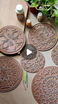 several wooden coasters sitting on top of a table next to plants and paint bottles