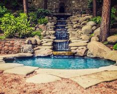 there is a small waterfall in the middle of this pool that has rocks around it