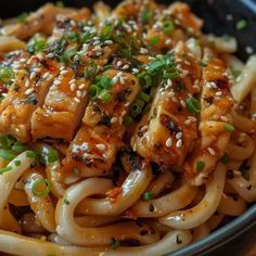 a bowl filled with noodles covered in sauce and topped with sesame seed sprinkles