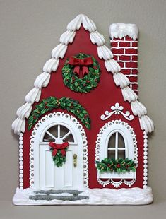 a red and white gingerbread house with wreaths on it