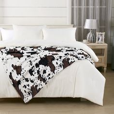 a cow print blanket is on top of a bed