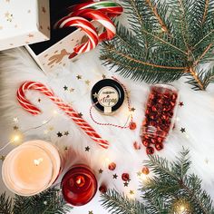 some candy canes and candles are on a white fur covered table with christmas decorations