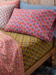 a bed topped with lots of pillows next to a wooden headboard