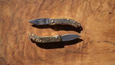 two knives sitting on top of a wooden table next to each other with metal handles