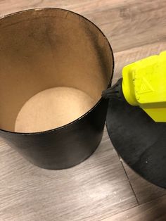 a yellow spatula sitting on top of a wooden table next to a black bowl