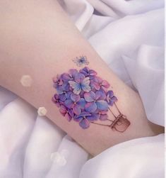 a woman's leg with purple flowers on it and a butterfly flying over the top