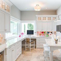 a kitchen with lots of white cabinets and counter top space in front of a window