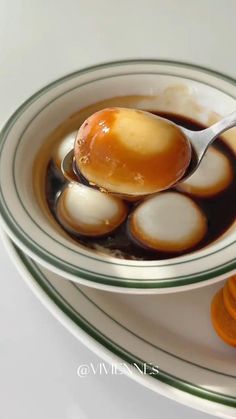 a spoon full of liquid sitting in a bowl next to sliced oranges on a plate