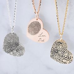 three necklaces with finger prints on them, one has a heart and the other has a fingerprint