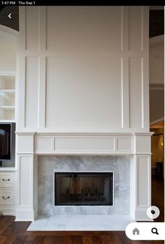 an empty fireplace with white walls and wood floors