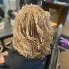 the back of a woman's head with blonde hair and bangs in a salon