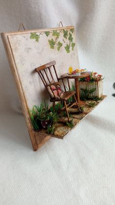 a miniature table and chairs are set up on a white surface with green plants growing out of them